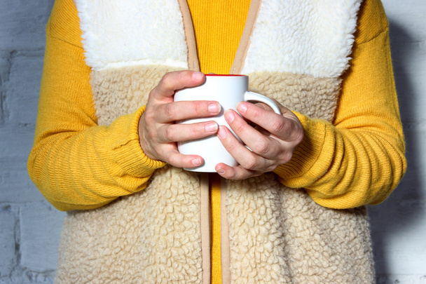 Woman holds a hot cup of tea and warms his hands - 写真・画像