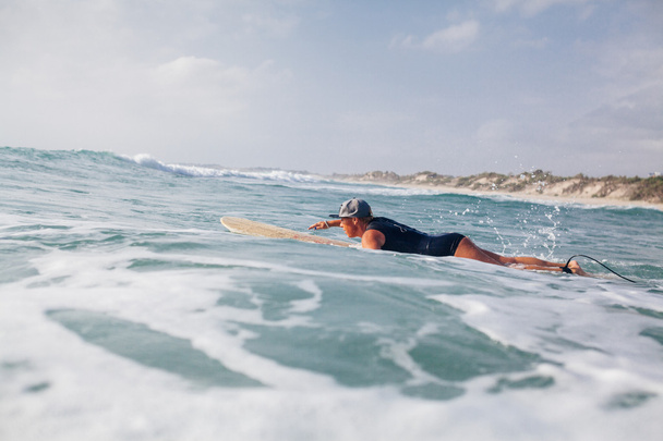 女性サーファーが海で泳いで - 写真・画像