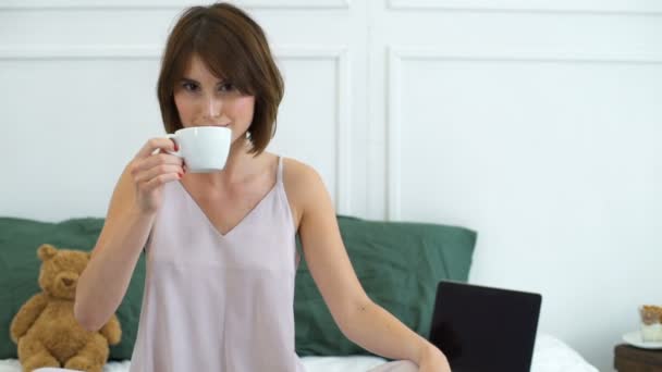όμορφη γυναίκα πίνοντας καφέ στο κρεβάτι αργή κίνηση - Πλάνα, βίντεο