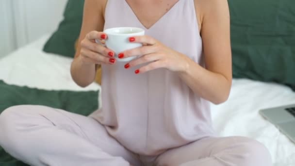 close up dolly shot of woman drinking coffee in bed - Video