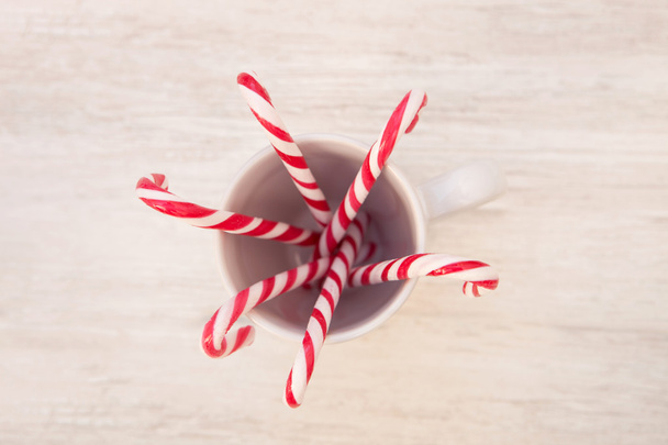 Kerstmis rood en wit candy canes in een kopje - Foto, afbeelding