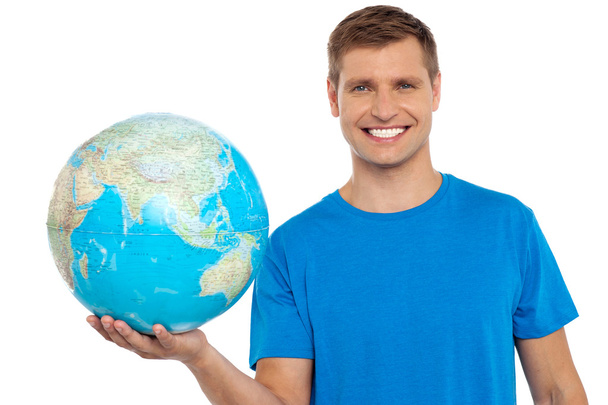 Young cheerful man holding a globe in his hand - Foto, afbeelding