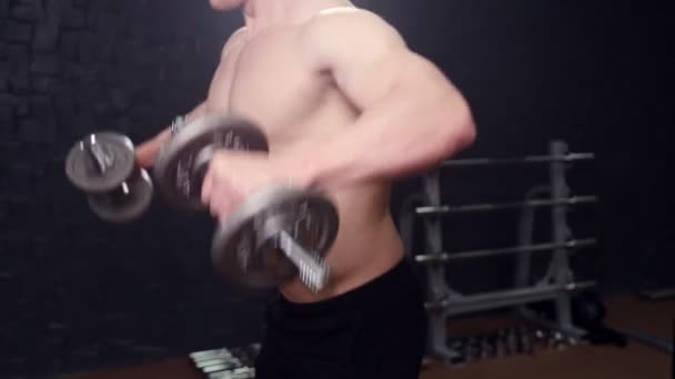 A man with a dumbbell in the gym - Felvétel, videó