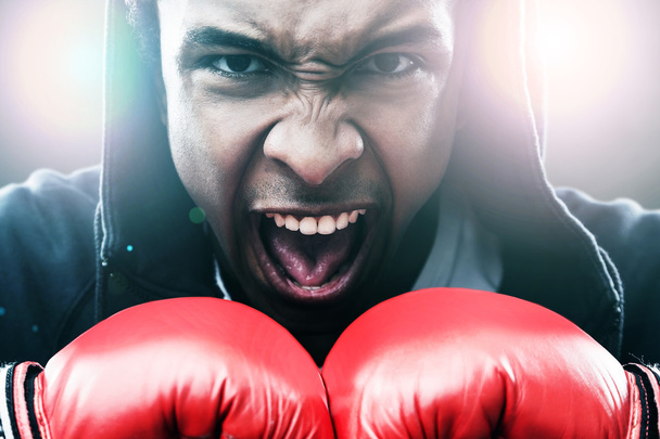 Close up of enraged African American man in boxing gloves. Concept of championship  - Photo, Image