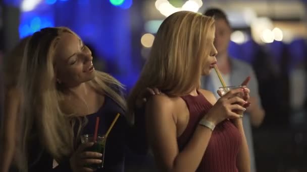 Two sexy blondes flirting with smiles on pretty faces, dancing at party in club - Footage, Video