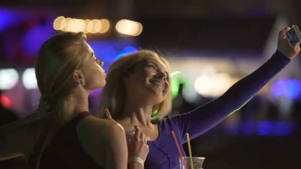 Podekscytowany Blondynki stwarzające dla selfie na dyskotece, co twarze do kamery smartphone - Materiał filmowy, wideo