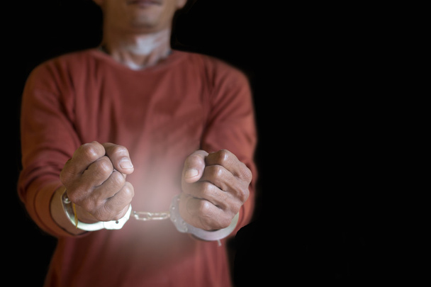 Bilincses kezek Egy férfi, akit bilinccsel a kezén tartóztattak le, női rabokat bilincseltek meg fekete alapon. - Fotó, kép