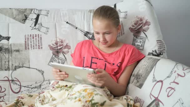 Teenager girl uses a digital tablet on the bed - Felvétel, videó