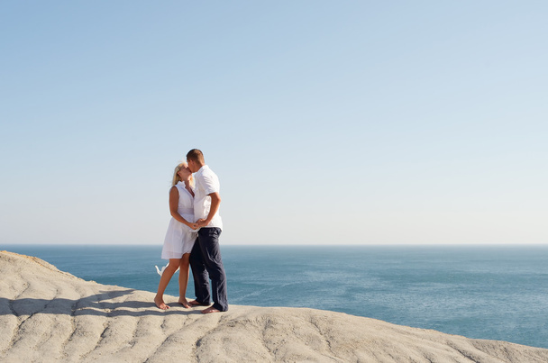 Young couple kissing while standing on a rock - Φωτογραφία, εικόνα