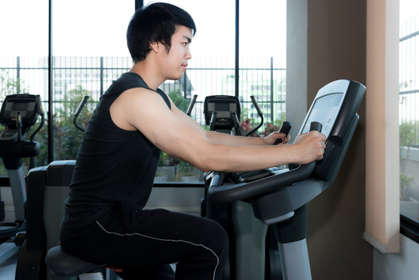 Człowiek w siłowni. Azjatycka młodego człowieka, ćwiczenia na nogi, robi cardio - Zdjęcie, obraz