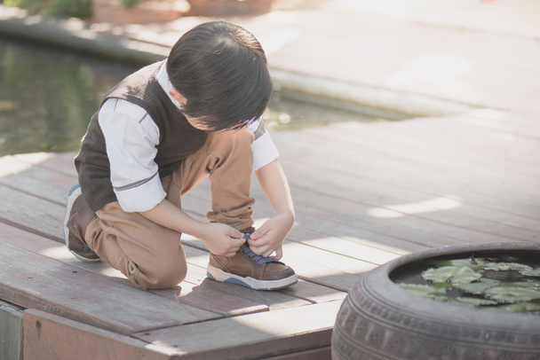 little asian boy tying his shoes - 写真・画像