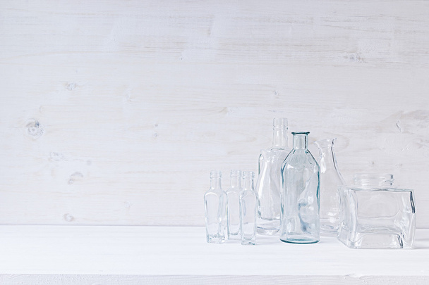 Empty transparent bottles on a white wood background. Home decor.  - Foto, imagen