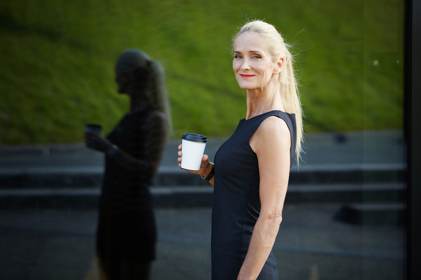 Content businesswoman holding cup of coffee - Zdjęcie, obraz