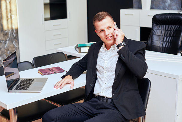 Young corporate executive sitting comfortably in a stylish chair, using a digital tablet, with gentle sunflare through the large windows of a modern office - Zdjęcie, obraz