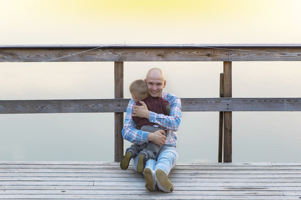 Padre e hijo bebé sentados en el puente de madera
. - Foto, Imagen