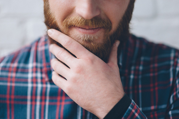 young man touches with hand his beard - Foto, imagen