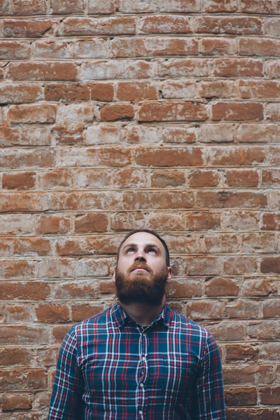 young man with beard against background of an old brick wall - Fotoğraf, Görsel
