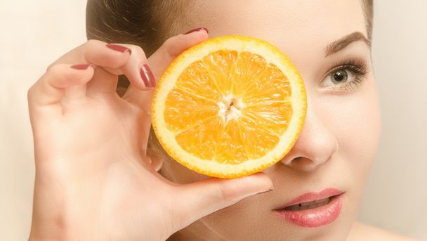 Young attractive woman with a slice of orange - Fotoğraf, Görsel