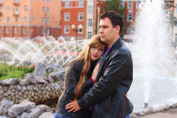 Man embraces woman in leather jacket near fountain - Photo, image