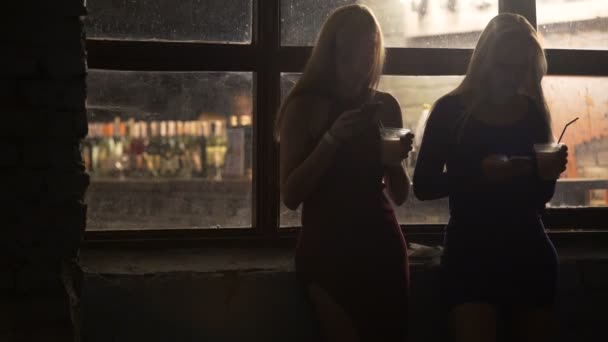 Beautiful young women checking messages on smartphones at dawn after party - Footage, Video