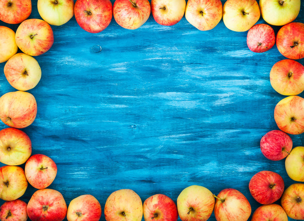Ramki z świeżych jabłek na pomalowane niebieskim tle drewnianych - Zdjęcie, obraz