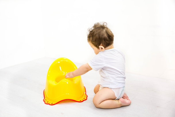 Infant child baby boy toddler play with potty toilet stool pot on a white background - Photo, Image