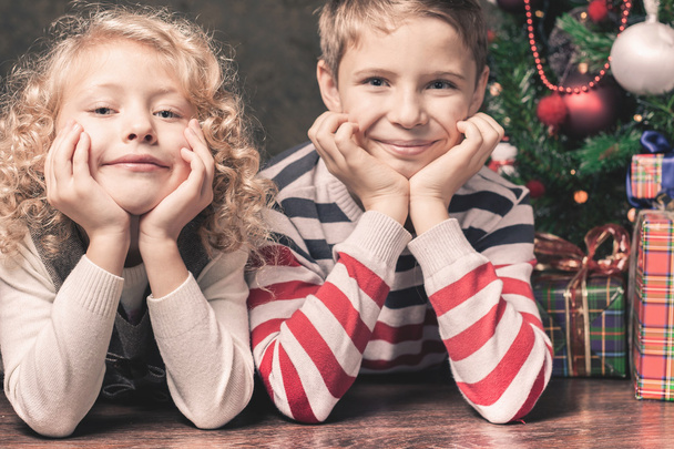 Glückliche Kinder liegen auf dem Boden unter dem Weihnachtsbaum. - Foto, Bild