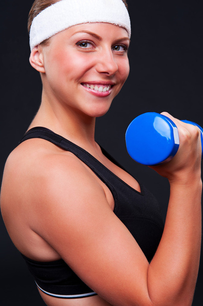 smiley sportswoman with blue dumbbells - Фото, изображение