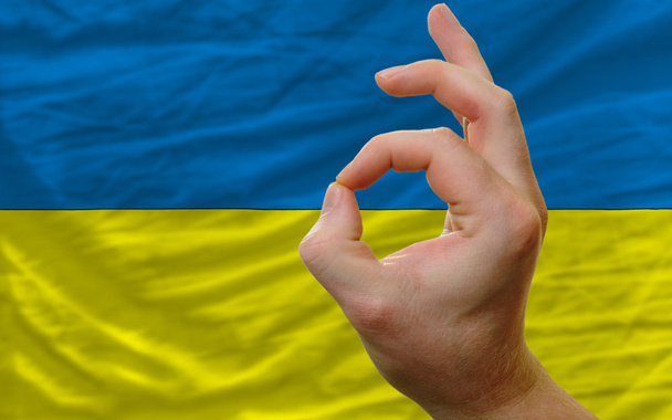 Εντάξει χειρονομία μπροστά από την εθνική σημαία της Ουκρανίας - Φωτογραφία, εικόνα