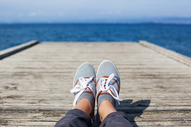 Woman feet in casual shoes on the wooden pier - Photo, image