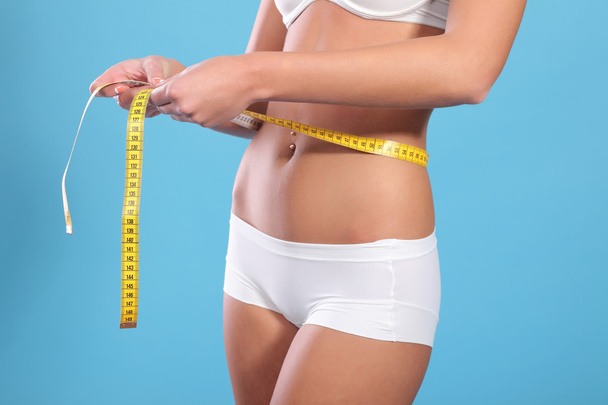 woman measuring waist on blue background - Photo, Image