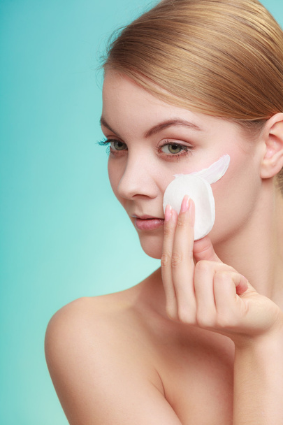 Woman removing makeup with cream and cotton pad - Photo, image