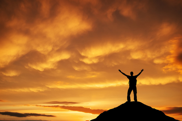 Silhueta de um homem no topo de uma montanha contra o céu do pôr do sol
.  - Foto, Imagem