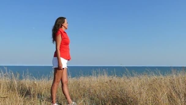 Αργή κίνηση. Λεπτή γυναίκα με κόκκινο στάση ενάντια στη θάλασσα. Εστίαση αλλαγής - Πλάνα, βίντεο