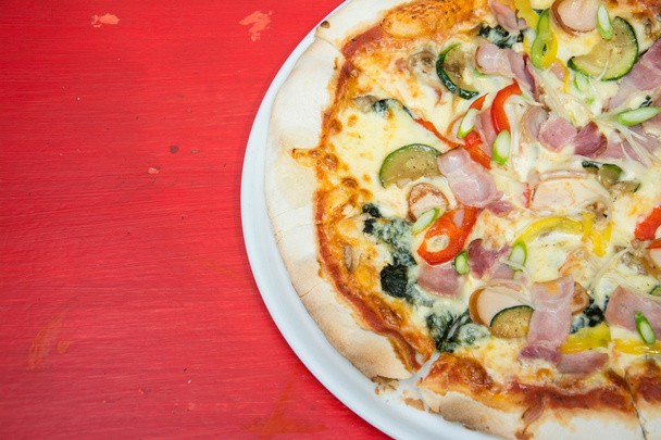 Tranche de pizza chaude au fromage fondu sur une table en bois rouge
. - Photo, image
