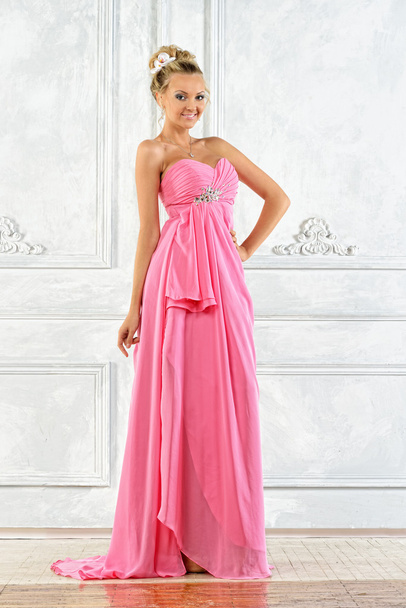Beautiful blonde woman in a pink evening long dress. - Foto, afbeelding