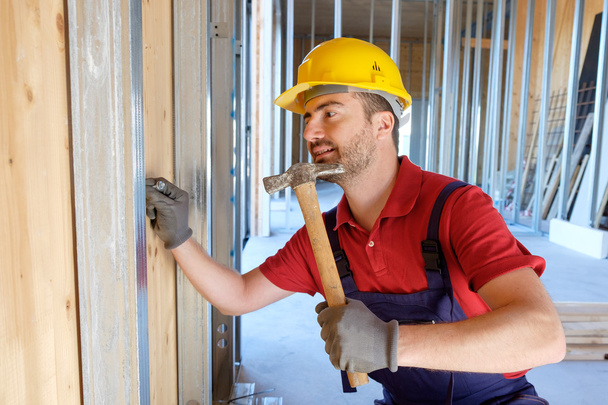 Carpintero usando martillo en un sitio de construcción
 - Foto, Imagen