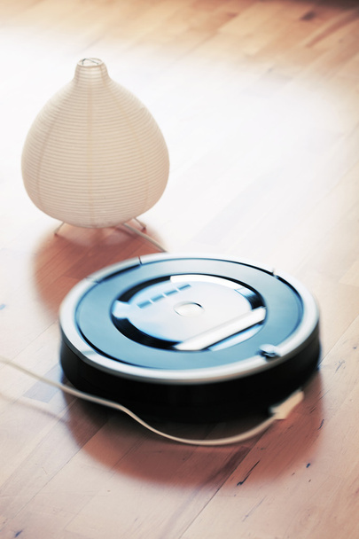 Ρομποτική ηλεκτρική σκούπα στο φυλλόμορφο ξύλινο πάτωμα για έξυπνη καθαρισμού ΣΕΚ - Φωτογραφία, εικόνα