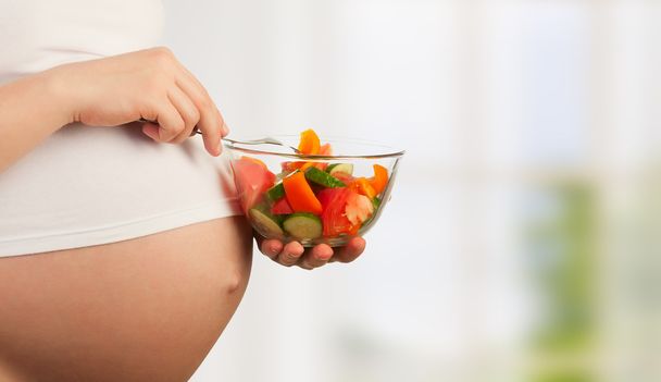 Healthy nutrition and pregnancy. pregnant woman and vegetable sa - Photo, Image