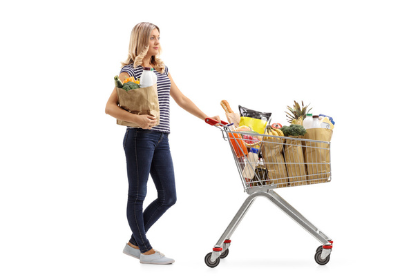 Woman waiting in line with shopping cart and paper bag - Photo, image
