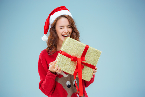 Girl dressed in santa hat with a Christmas gift - Фото, изображение