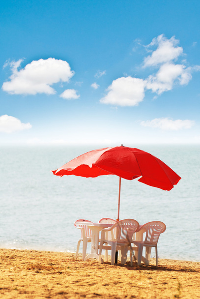 Tafel, stoelen en parasol op het strand - Foto, afbeelding