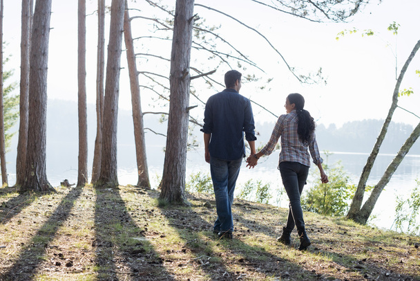 casal andando à sombra de pinheiros
 - Foto, Imagem