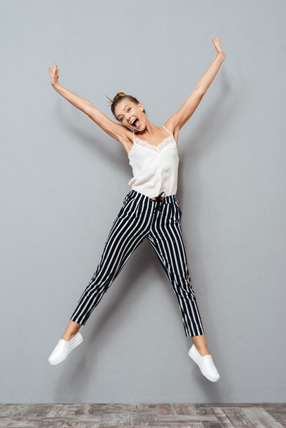 Full length portrait of a cheerful cute woman jumping - Foto, afbeelding