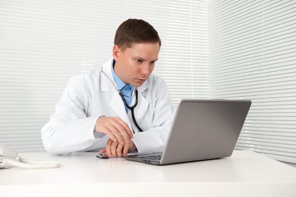 Doctor sitting at his desk with laptop computer - Foto, Imagem