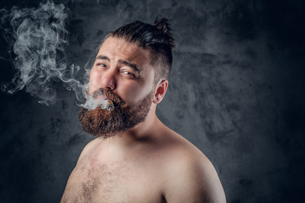 Varón barbudo fumando un cigarro
 - Foto, imagen