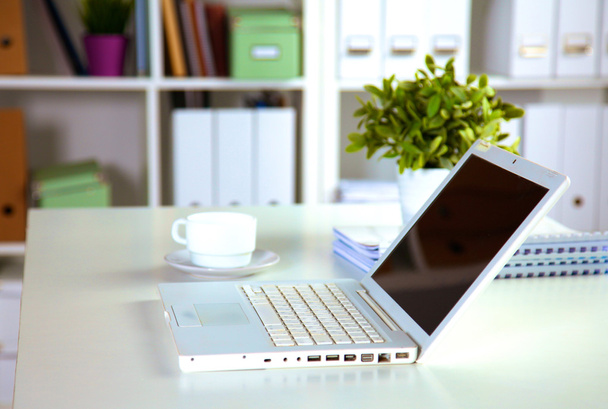 Close-up van een werk bureau interieur met laptopcomputer, kopje koffie en witte gordijnen op zonnige dag - Foto, afbeelding