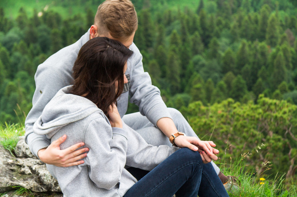 Happy young couple in love sitting on a mountain, hugging and lo - Photo, image
