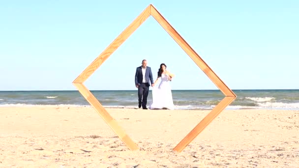 Frischverheiratete spazieren am Meeresufer entlang - Filmmaterial, Video