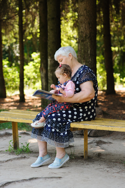 Abuela y nieta leyendo el libro en el parque
 - Foto, Imagen